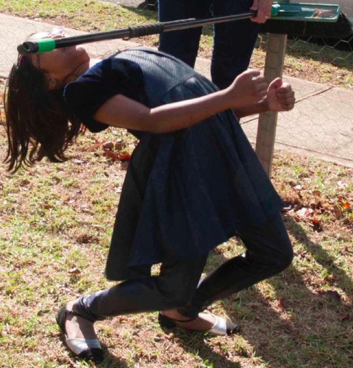 Young girl doing the limbo under a stick