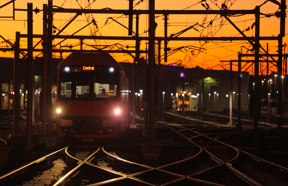 Train rolling into Sydney station on dusk with street lights illuminated